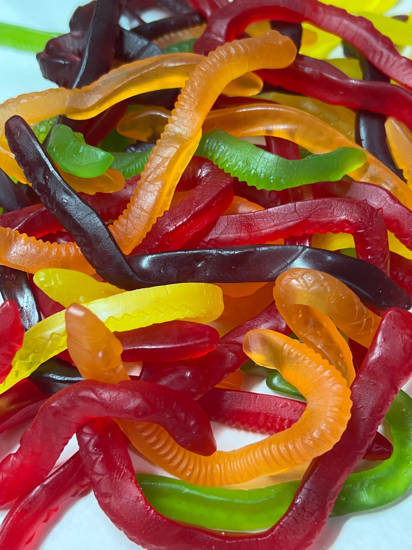 Colorful assortment of Allens Snakes lollies in red, green, yellow, orange, and black flavors
