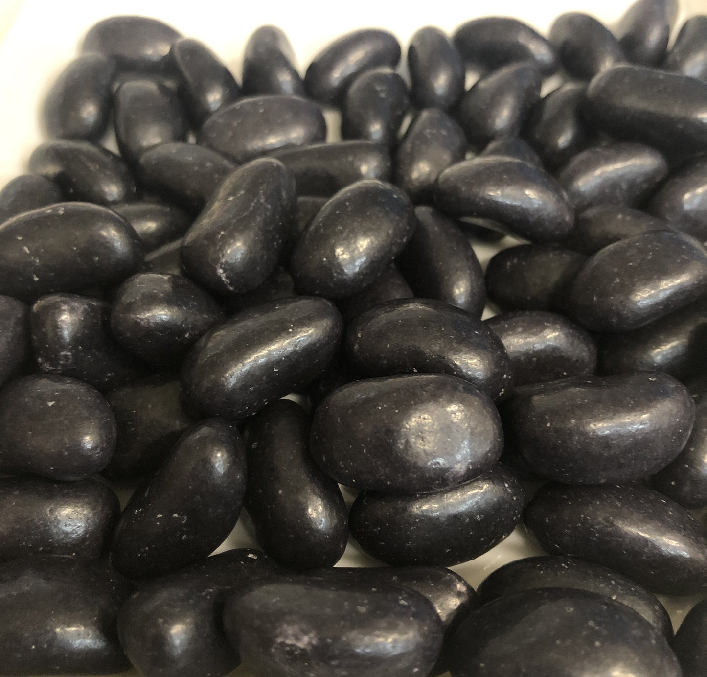 Close-up of SelectSweets black jelly beans piled together with a shiny smooth coating