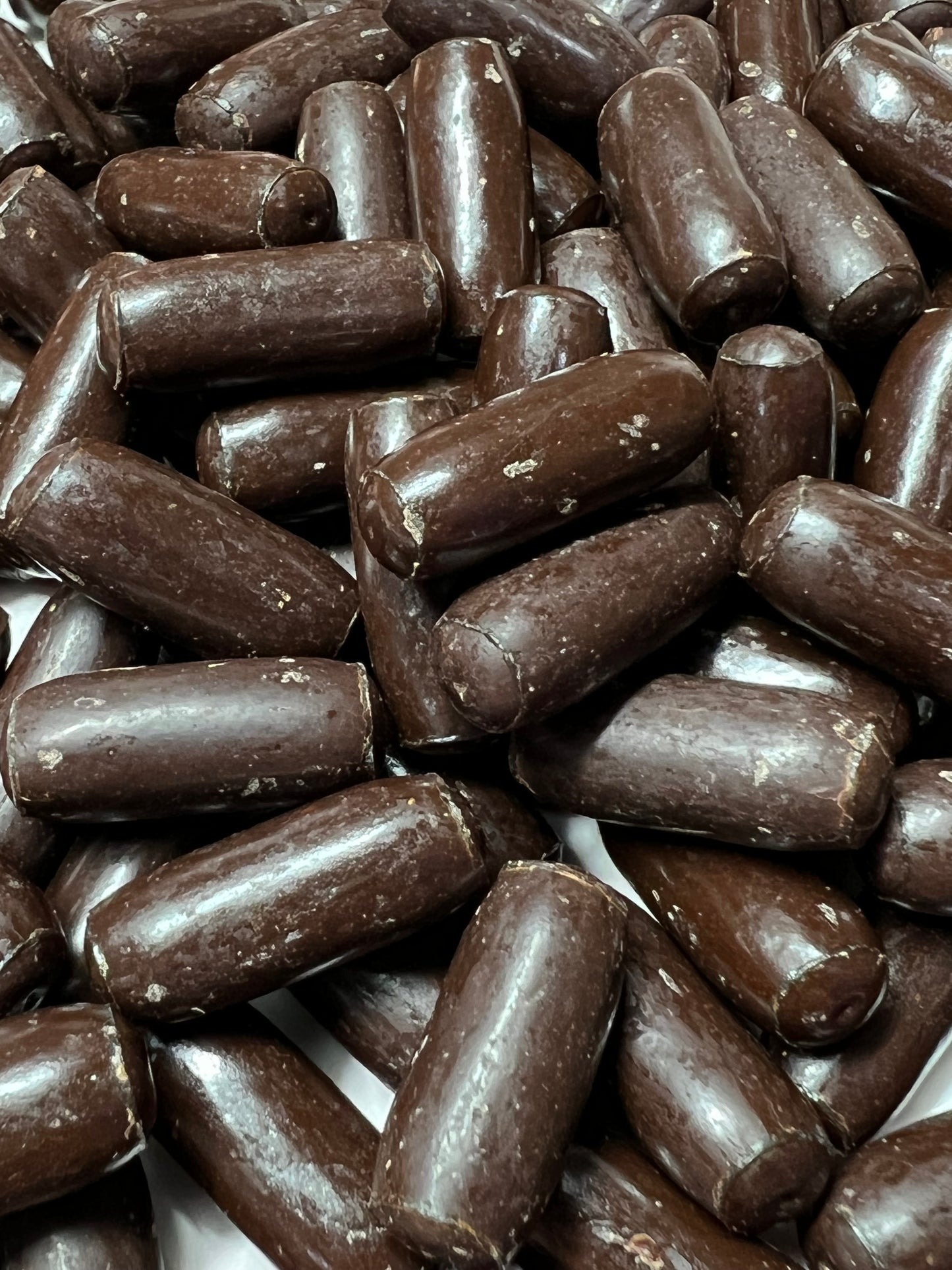 Close-up of SelectSweets dark chocolate licorice bullets with smooth glossy coating