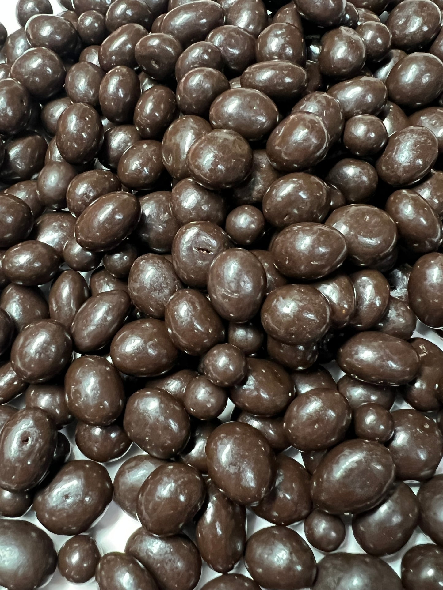 Close-up view of glossy dark chocolate peanuts by SelectSweets with smooth chocolate coating
