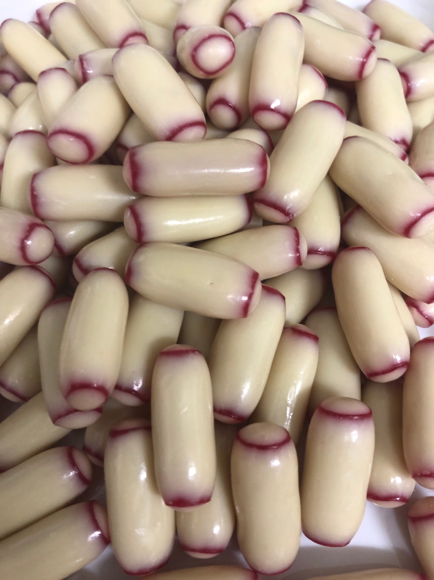 Close up of white chocolate raspberry bullets with creamy white coating and raspberry red tips