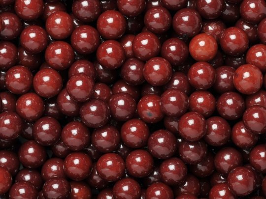 Close-up of SelectSweets1 glossy dark red aniseed balls candy with smooth round surfaces