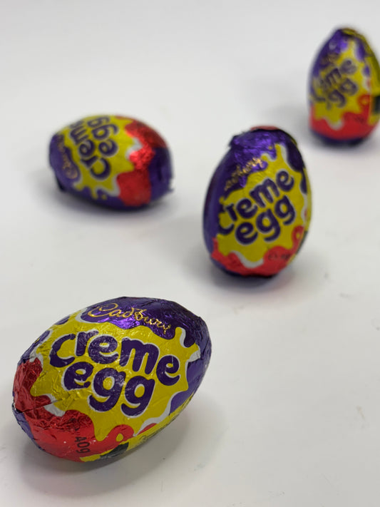 Four Cadbury Egg chocolate treats with colorful wrappers on a white background