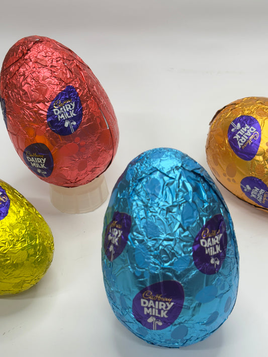 Colorful foil-wrapped milk chocolate egg in blue, surrounded by other chocolate eggs in red, yellow, and gold