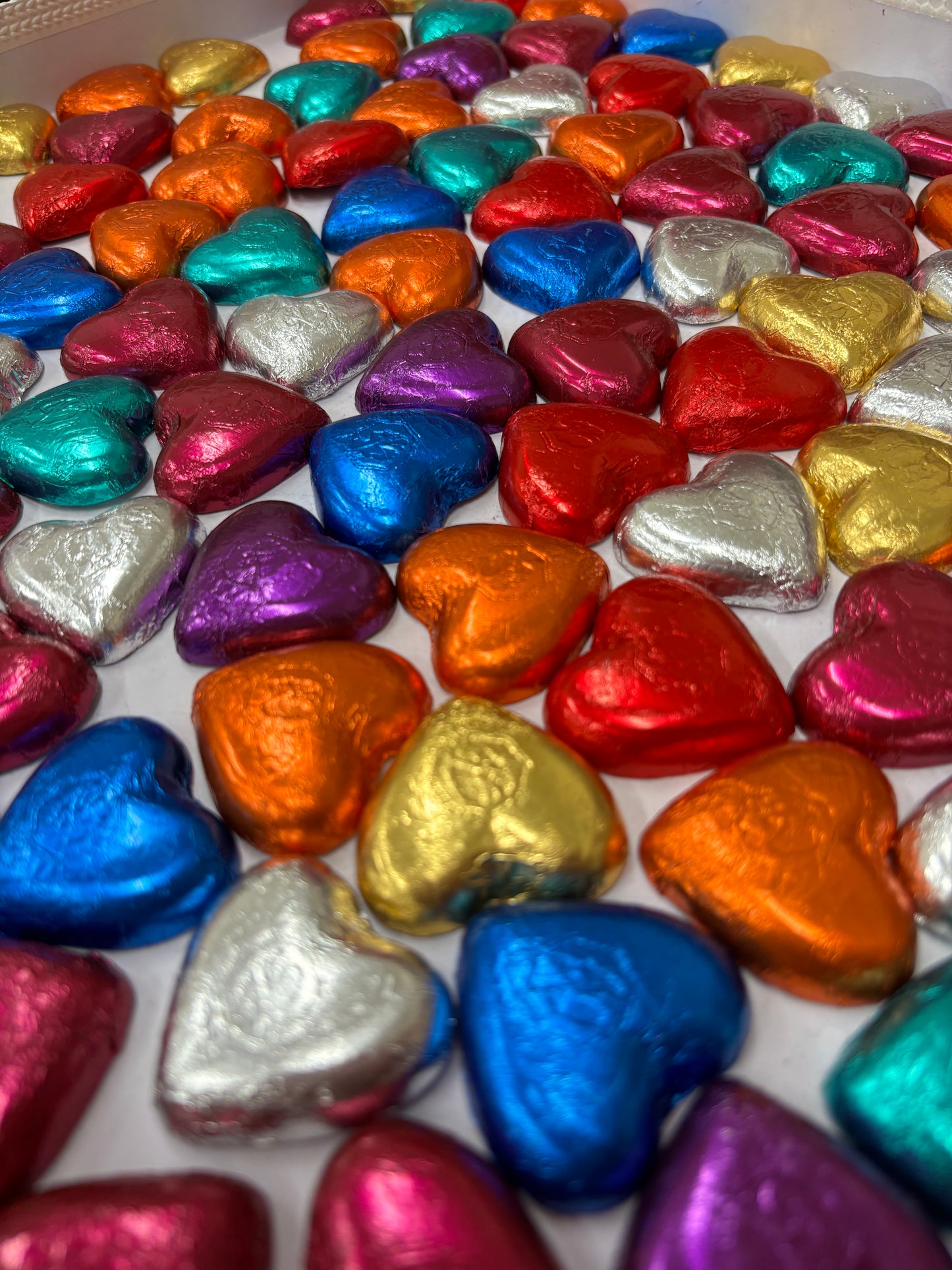 Colorful assortment of milk chocolate heart candies wrapped in shiny foil in various colors