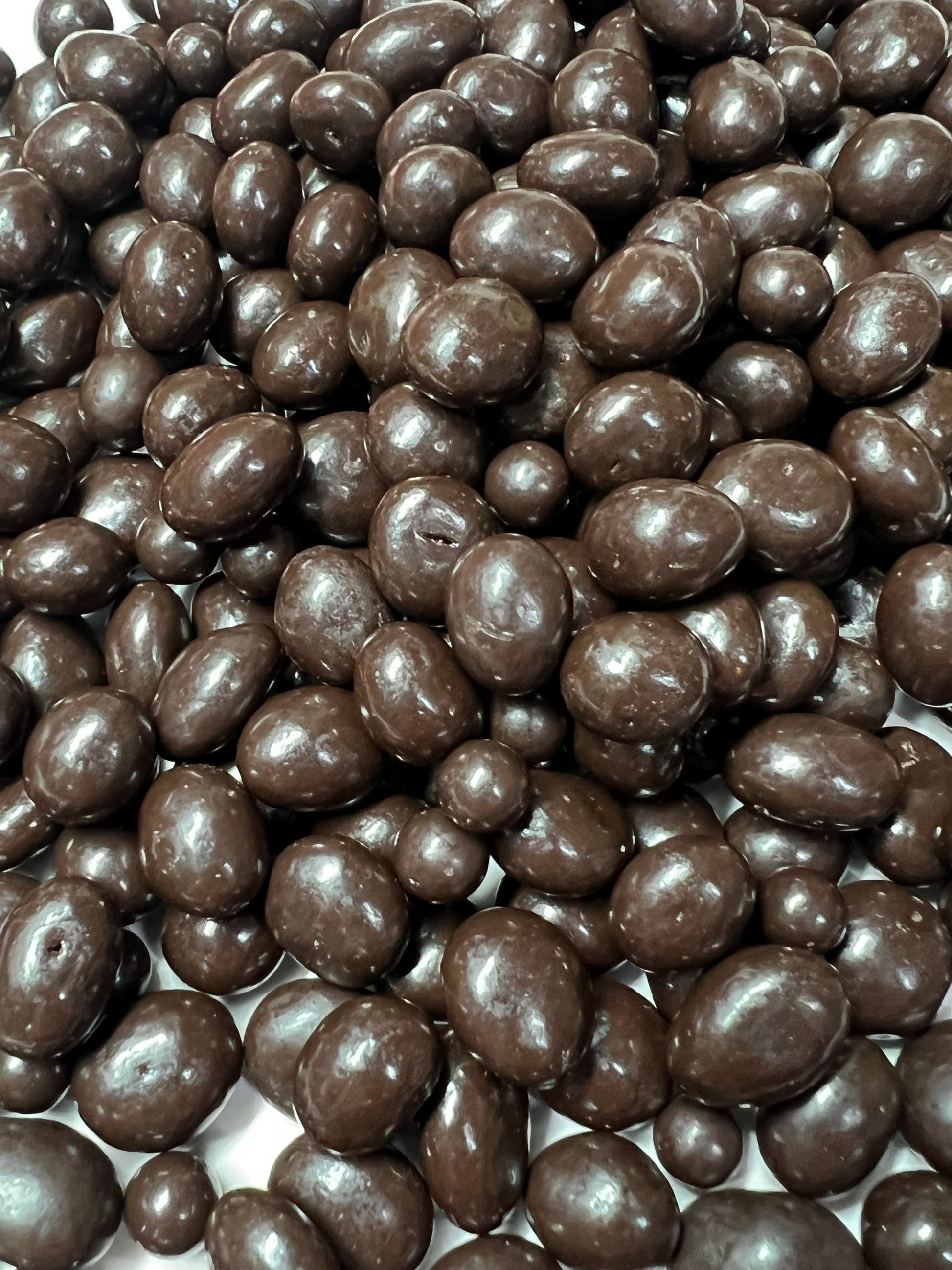 Close-up view of glossy dark chocolate peanuts by SelectSweets with smooth chocolate coating