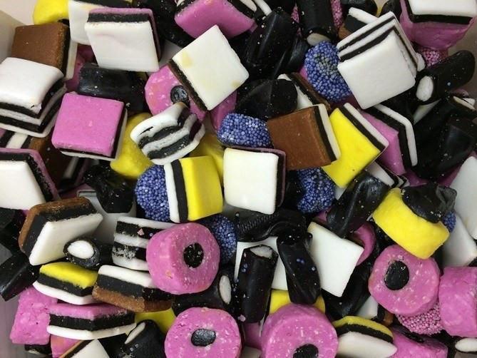 Colorful mix of English licorice allsorts candy in various shapes and colors including pink, yellow, black, white, and brown