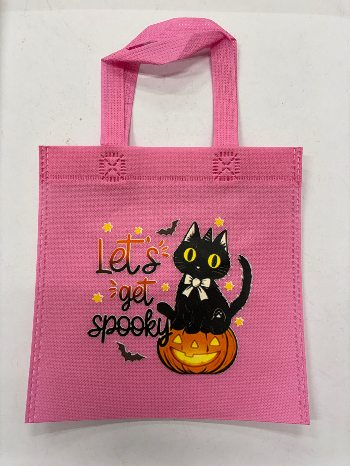 Pink Halloween tote bag featuring a black cat sitting on a pumpkin with spooky text