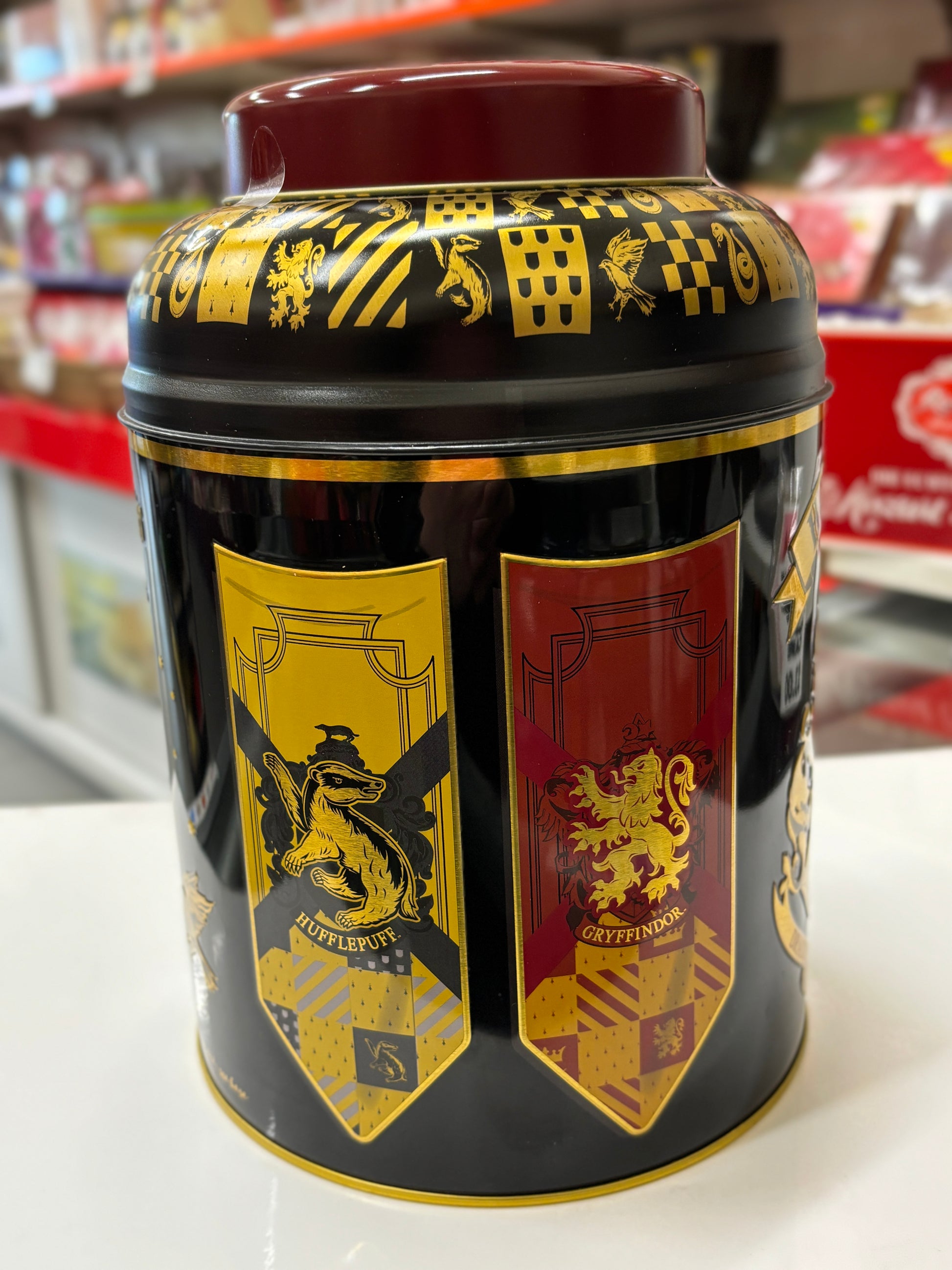 Hogwarts English tea tin featuring colorful house emblems for decorative storage