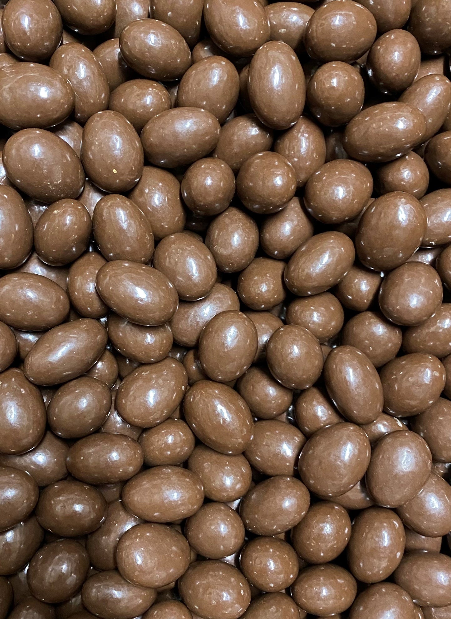 Close-up of SelectSweets milk chocolate scorched almonds with smooth glossy coating