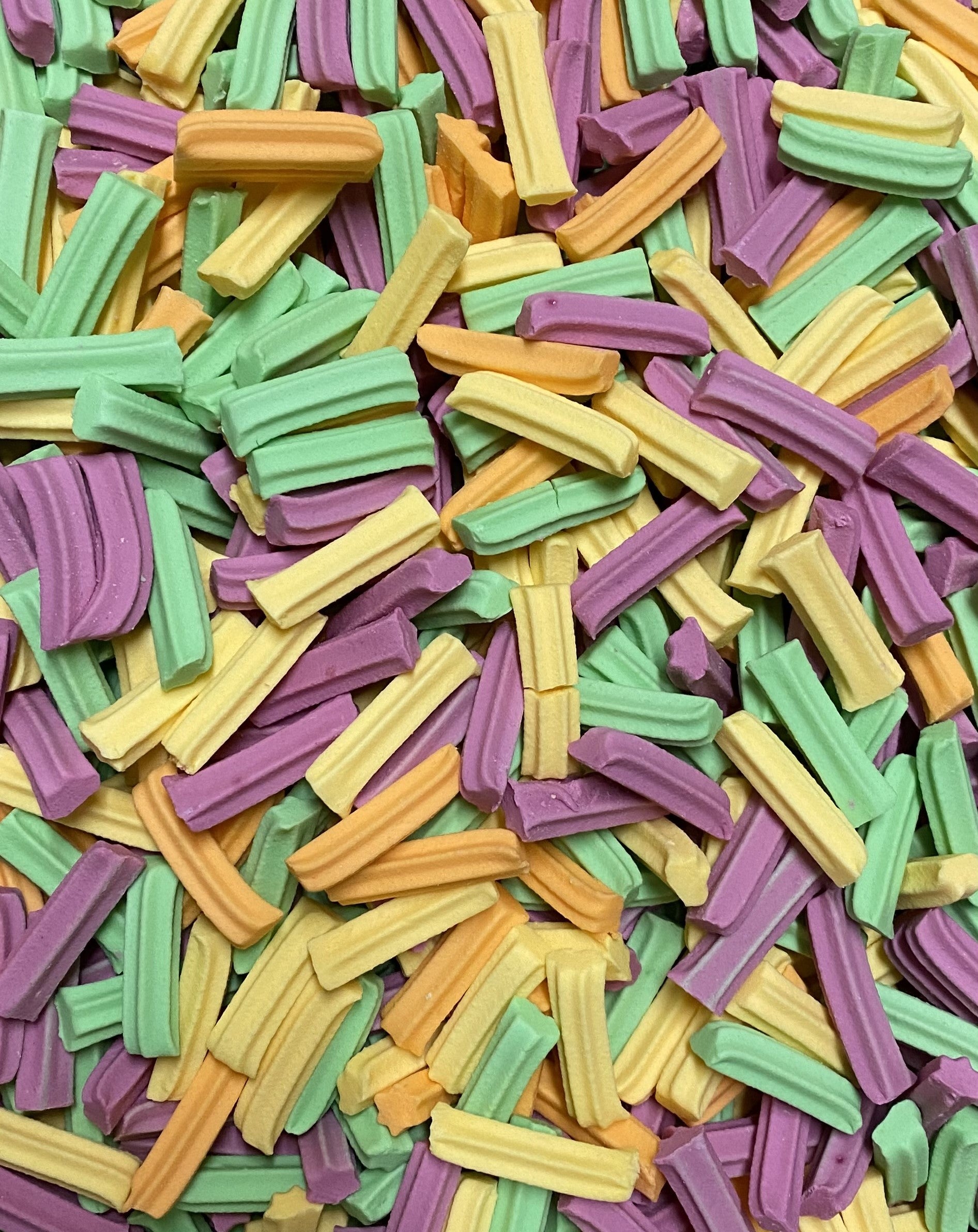 Colorful mini fruit candy sticks in green yellow orange and purple by Select Sweets