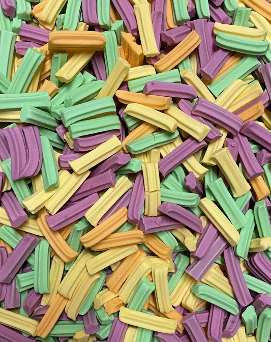 Colorful mini fruit candy sticks in green yellow orange and purple by Select Sweets