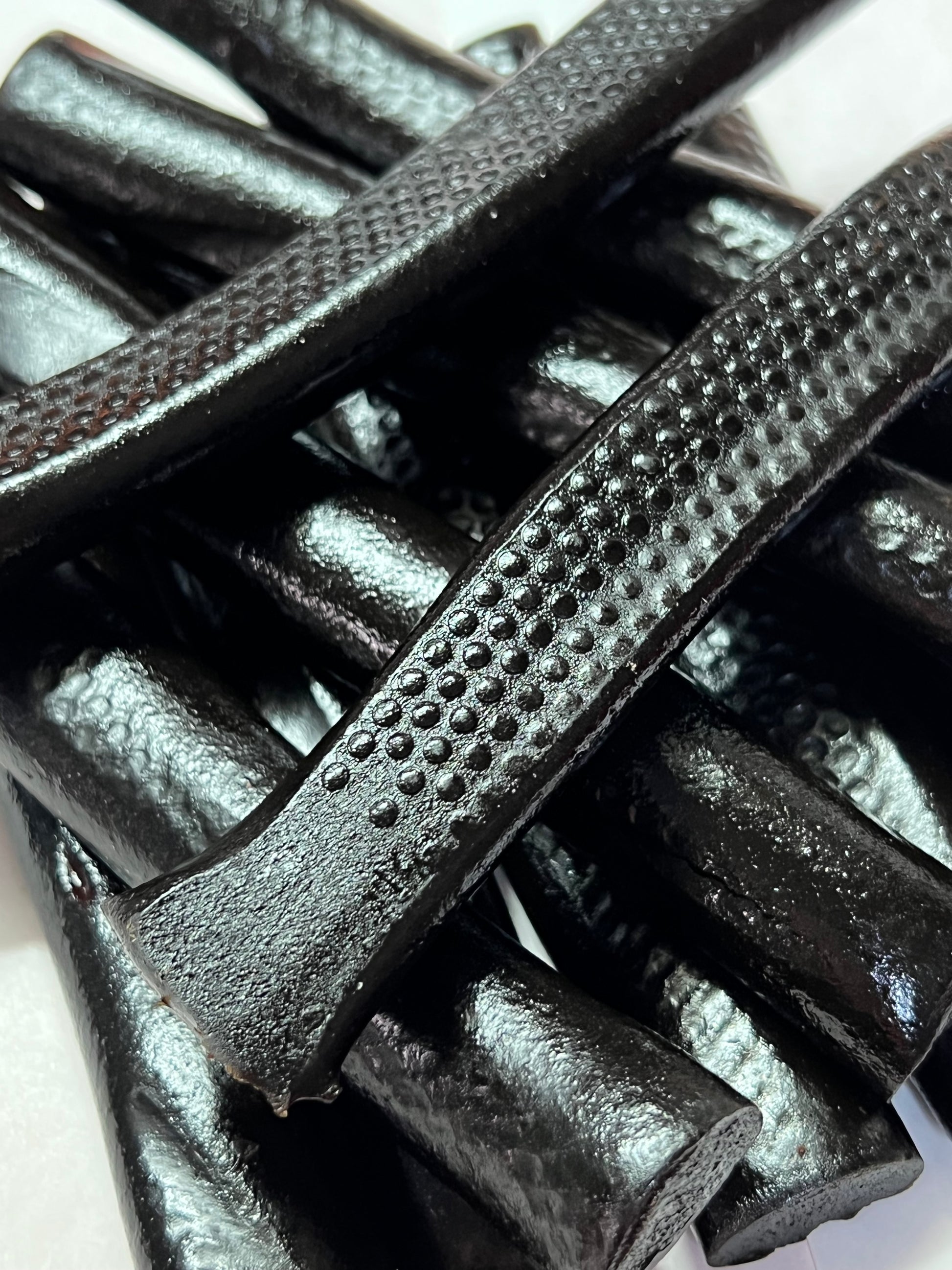 Old fashioned molasses licorice sticks in a close-up view showcasing their shiny texture