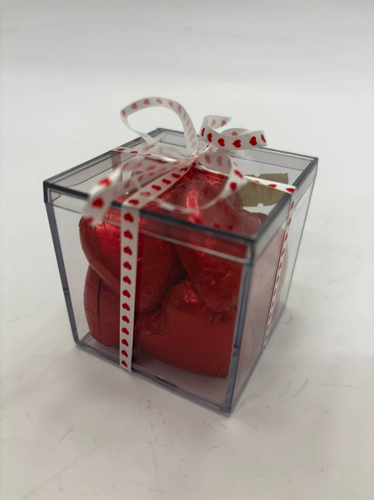 Gift box containing pink lady chocolate hearts wrapped in red foil with a decorative ribbon