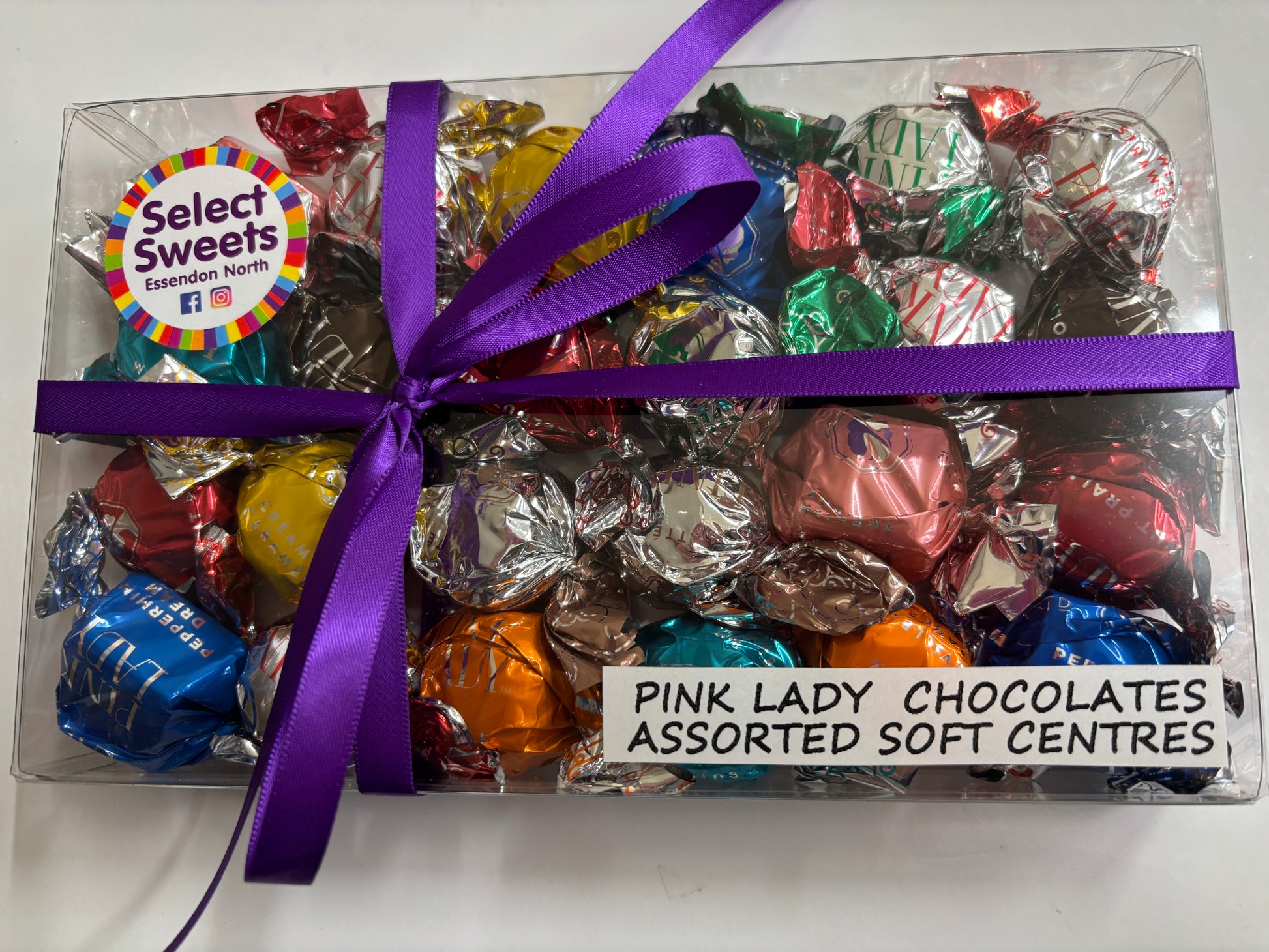 Select Sweets clear gift box of Pink Lady chocolates assorted foil wrapped soft center sweets with purple ribbon
