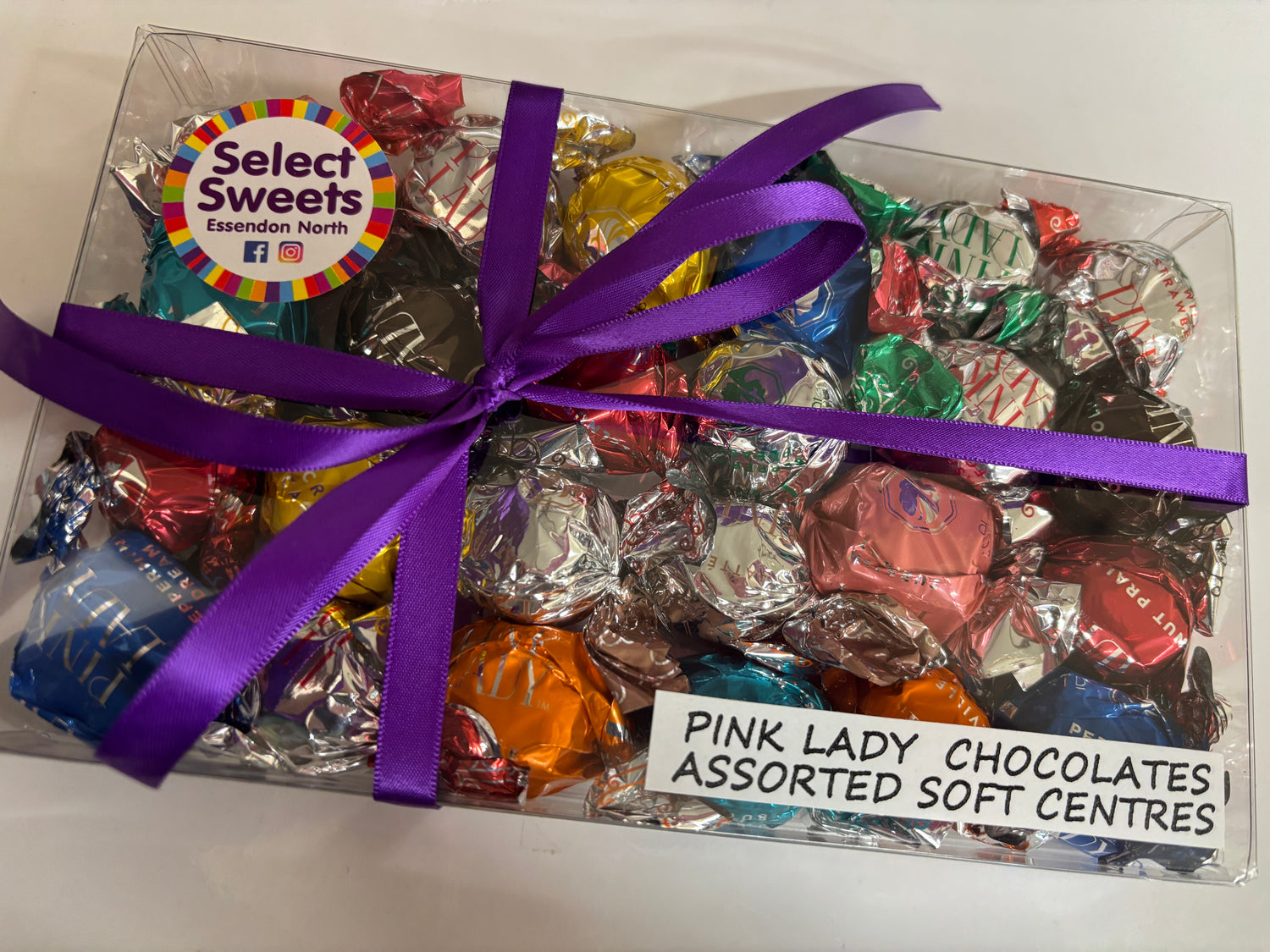 Select Sweets clear gift box of Pink Lady chocolates assorted soft centres in colorful foil with purple ribbon