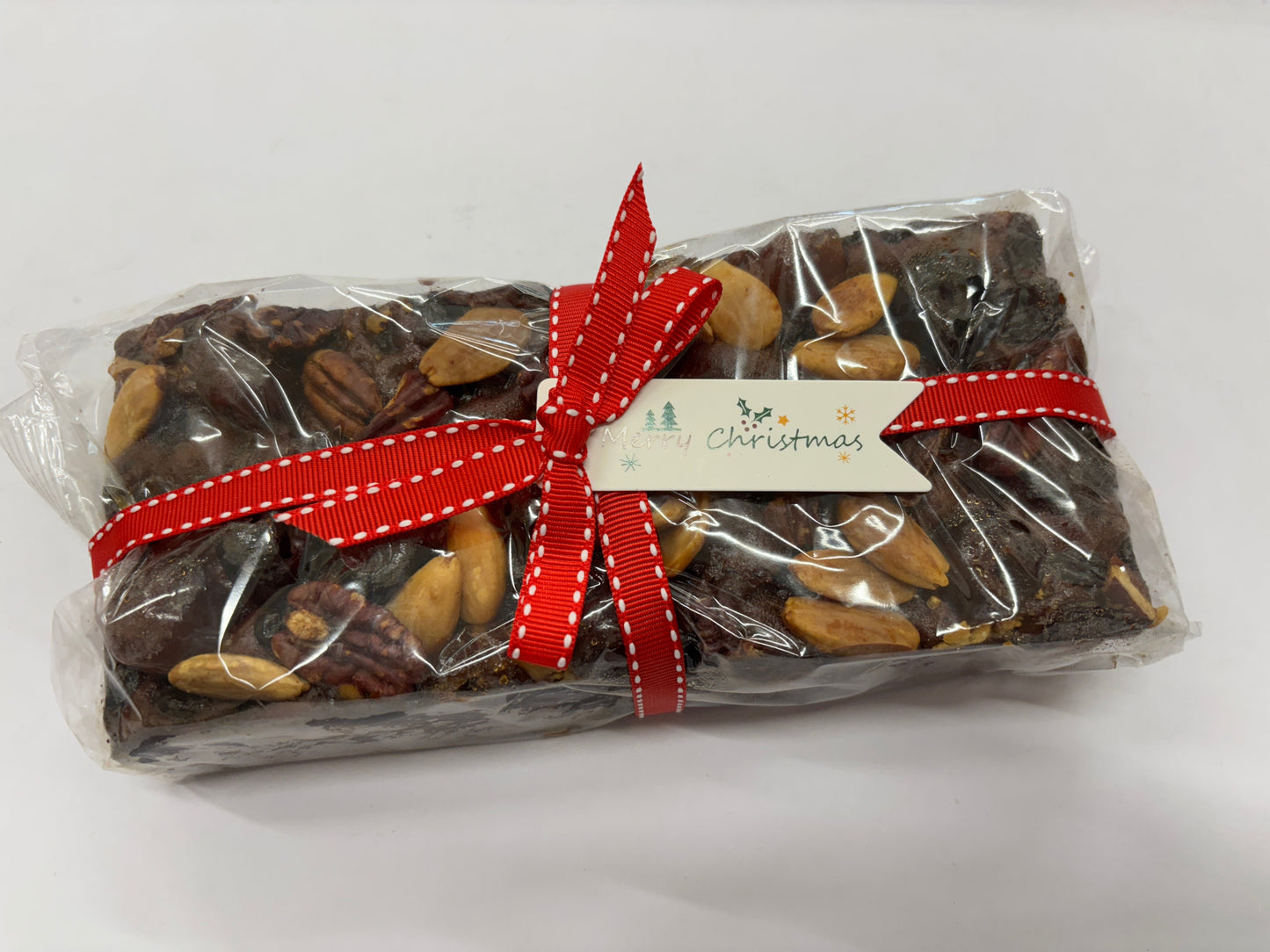 Delicious traditional Christmas fruit cake decorated with nuts and festive ribbon for holiday celebrations